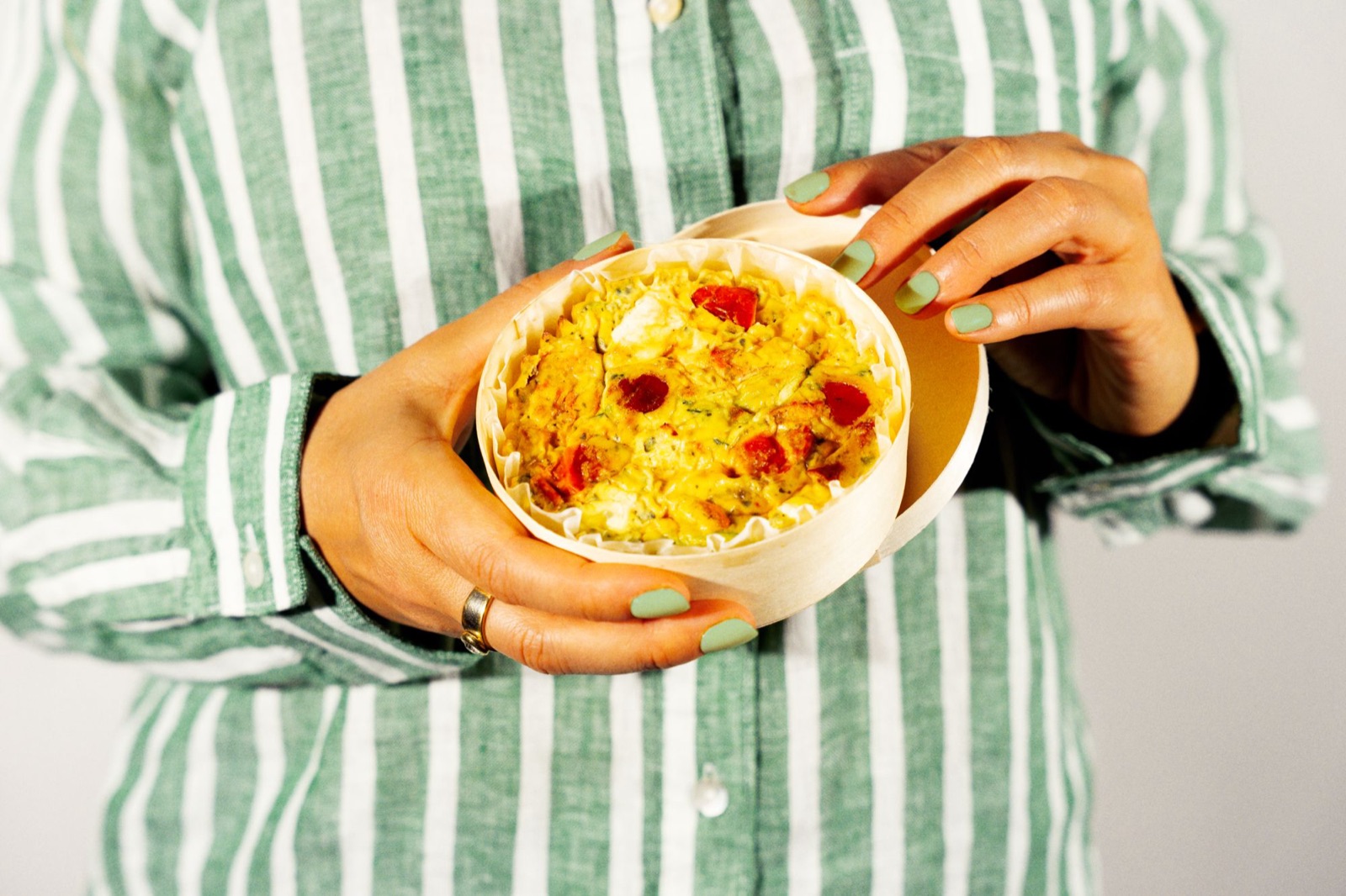 Quiche sans pâte dans sa boîte en bois, tenue à deux mains.